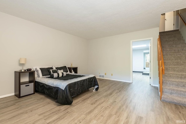 bedroom with light wood-type flooring and a textured ceiling