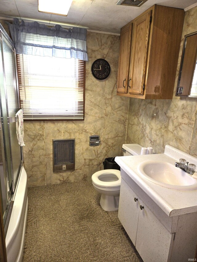 full bathroom featuring vanity, toilet, bath / shower combo with glass door, and tile walls