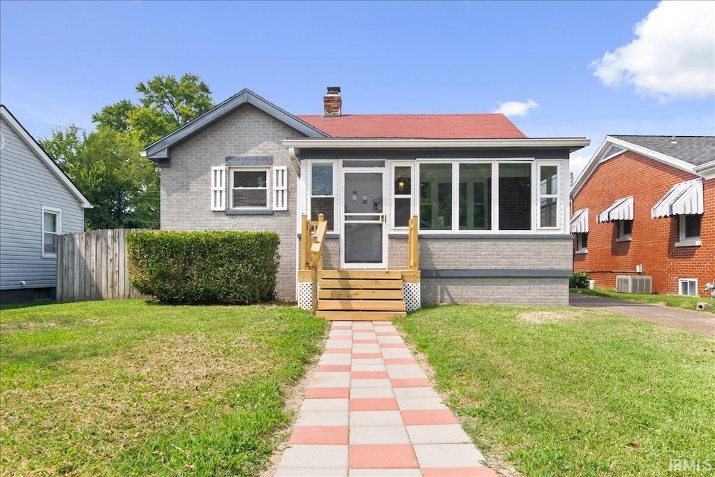 bungalow with central AC unit and a front yard