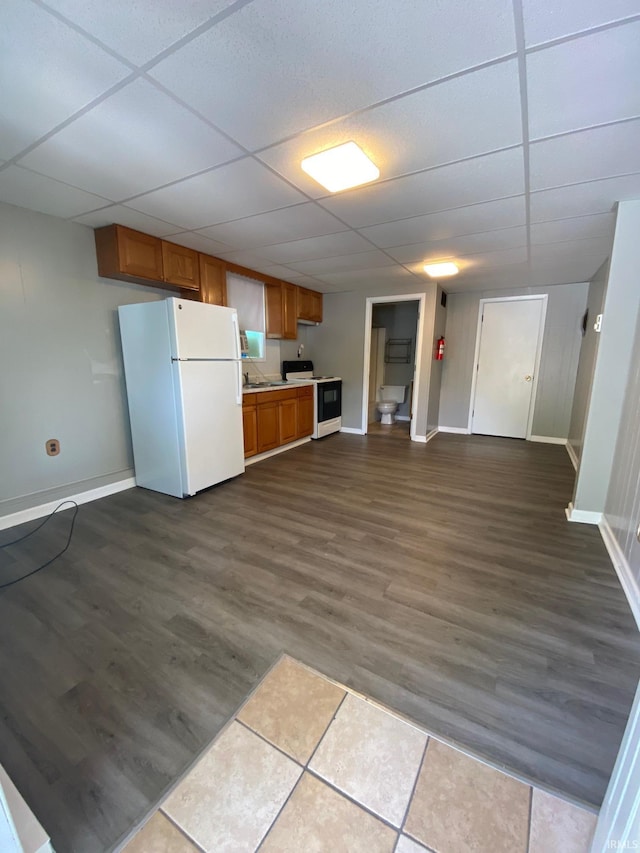 kitchen with white appliances, dark hardwood / wood-style floors, and a drop ceiling