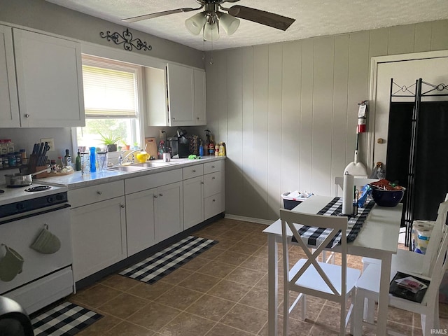 kitchen featuring white electric range, ceiling fan, white cabinetry, a textured ceiling, and dark tile patterned flooring