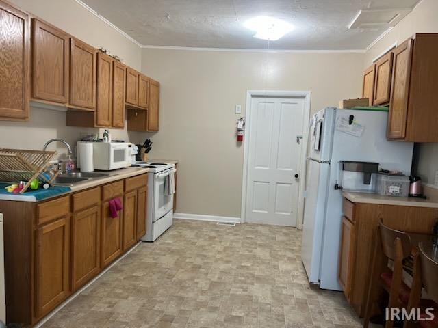 kitchen featuring crown molding, sink, and white appliances