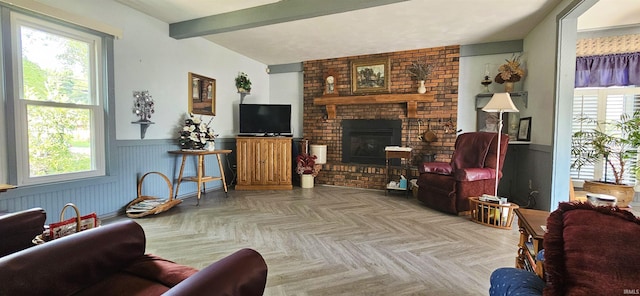 living area featuring a fireplace, wainscoting, beam ceiling, and a wealth of natural light