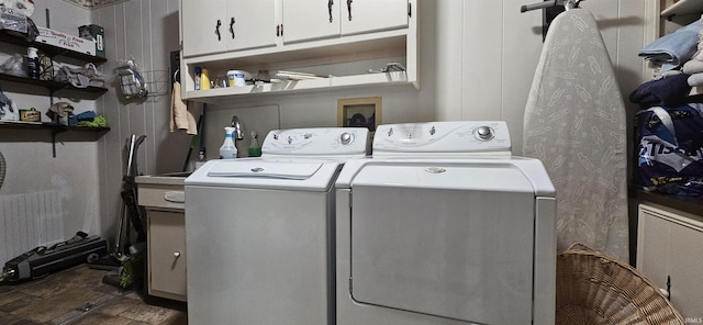 clothes washing area featuring cabinet space and washer and clothes dryer