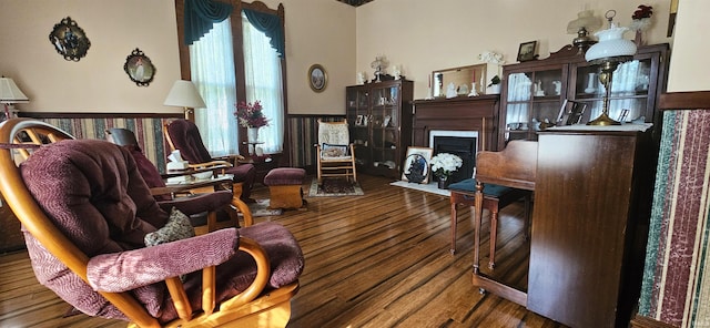 sitting room with a wealth of natural light, wood finished floors, and a fireplace with flush hearth