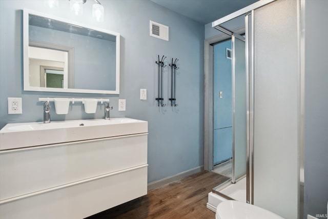 bathroom featuring toilet, hardwood / wood-style floors, vanity, and an enclosed shower