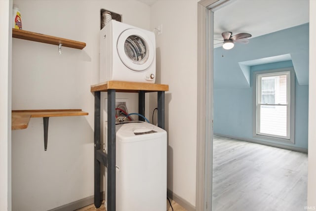 clothes washing area featuring stacked washer and clothes dryer, light wood-type flooring, and ceiling fan