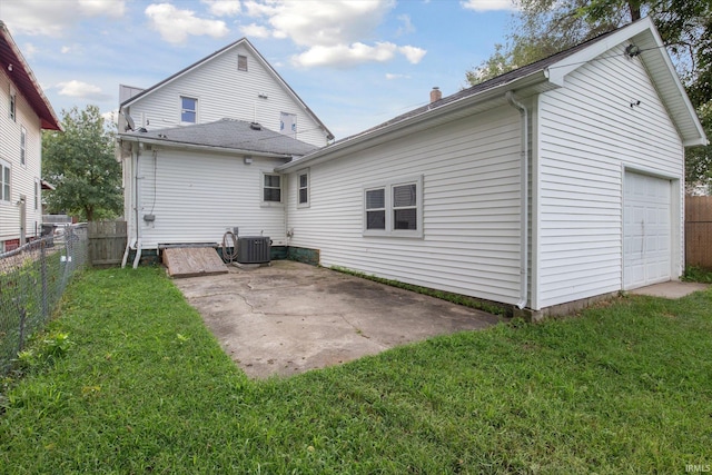 rear view of house featuring a garage, a patio, central AC, and a yard