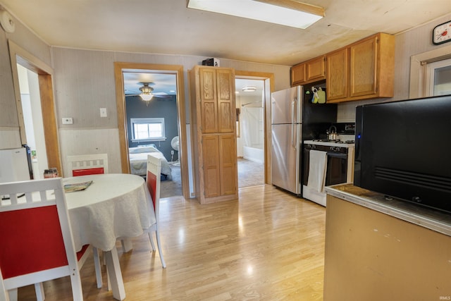 kitchen featuring stainless steel refrigerator, ceiling fan, gas range gas stove, and light hardwood / wood-style flooring