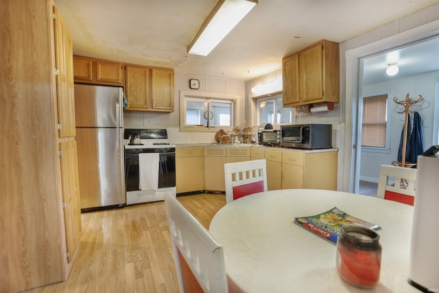 kitchen with stainless steel refrigerator, light hardwood / wood-style floors, and white range oven