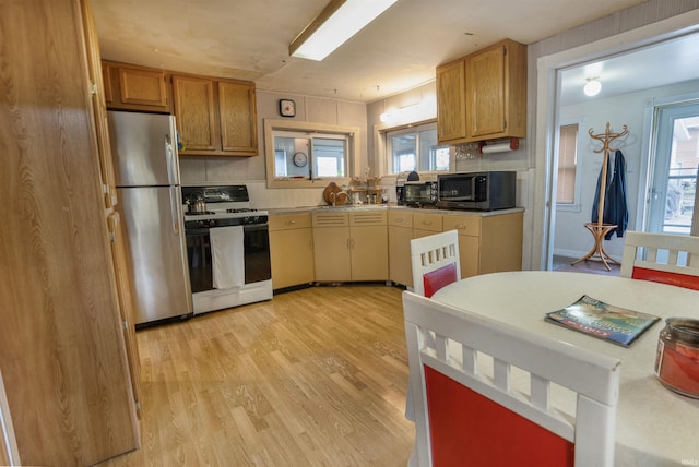 kitchen featuring stainless steel refrigerator, gas range oven, and light wood-type flooring