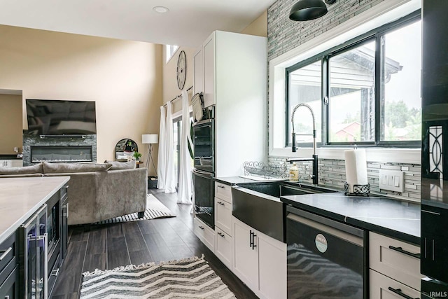 kitchen featuring white cabinetry, dishwashing machine, plenty of natural light, dark hardwood / wood-style floors, and a stone fireplace