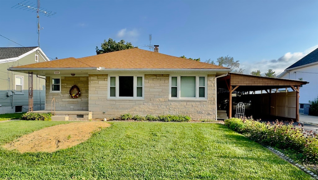 view of front facade with a carport, a front yard, stone siding, and roof with shingles