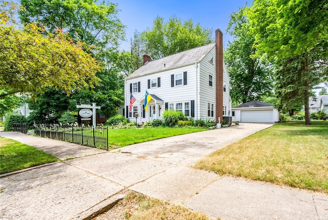 colonial home featuring a garage, an outbuilding, and a front yard