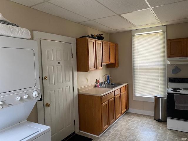 kitchen featuring white electric range, stacked washer / dryer, a paneled ceiling, and light tile patterned flooring