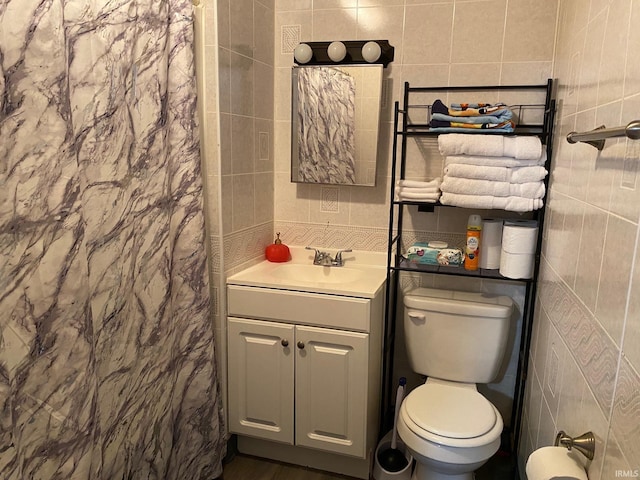 bathroom featuring vanity, toilet, and tile walls