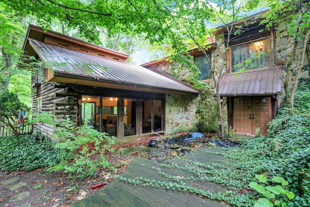 back of property featuring metal roof and stone siding