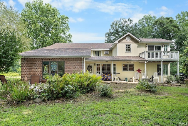 rear view of property with a balcony and a lawn