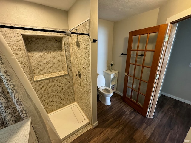 bathroom with a tile shower, hardwood / wood-style flooring, and toilet