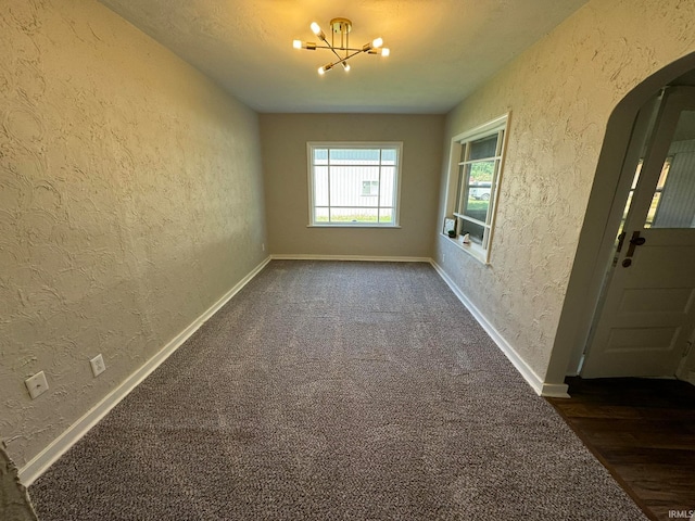 carpeted spare room featuring an inviting chandelier