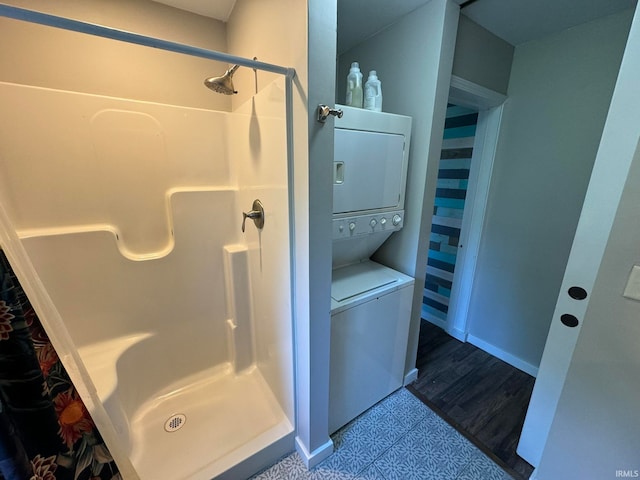 bathroom with walk in shower, stacked washing maching and dryer, and tile patterned flooring