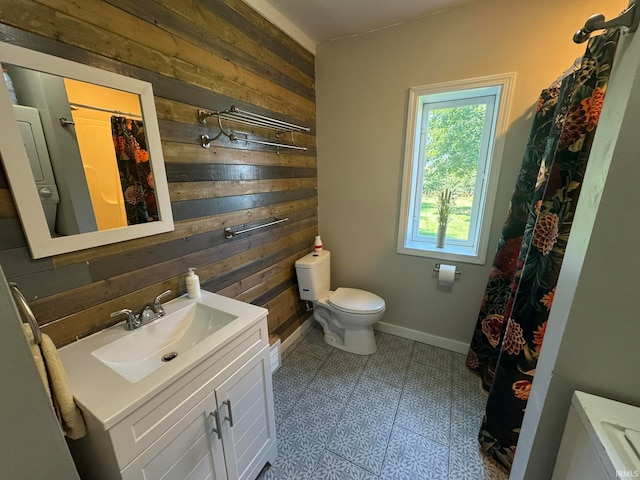 bathroom with tile patterned floors, vanity, wooden walls, and toilet