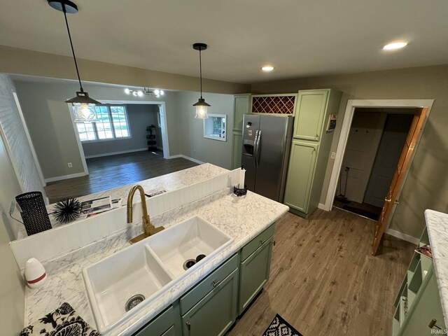 kitchen with pendant lighting, stainless steel fridge with ice dispenser, light wood-type flooring, green cabinets, and sink