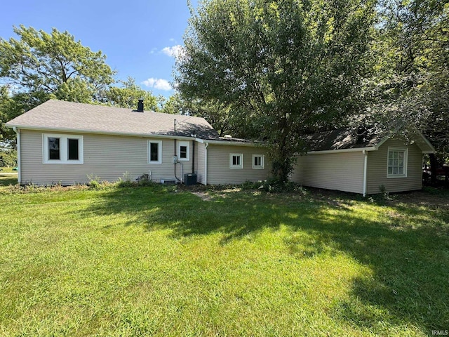 back of property featuring cooling unit and a yard