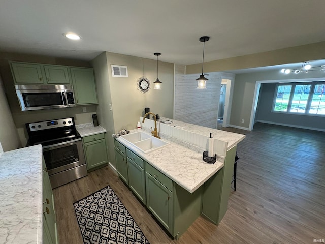 kitchen featuring dark wood-type flooring, stainless steel appliances, light stone countertops, green cabinets, and sink