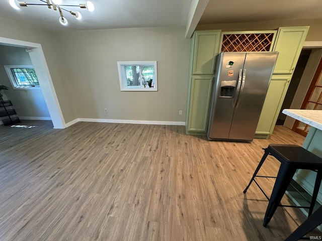 kitchen featuring light hardwood / wood-style flooring, green cabinets, and stainless steel refrigerator with ice dispenser