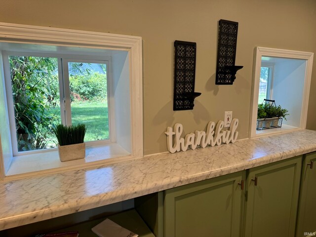 kitchen with green cabinetry, plenty of natural light, and light stone countertops