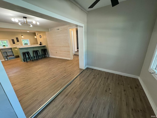 unfurnished living room featuring dark hardwood / wood-style floors and ceiling fan with notable chandelier