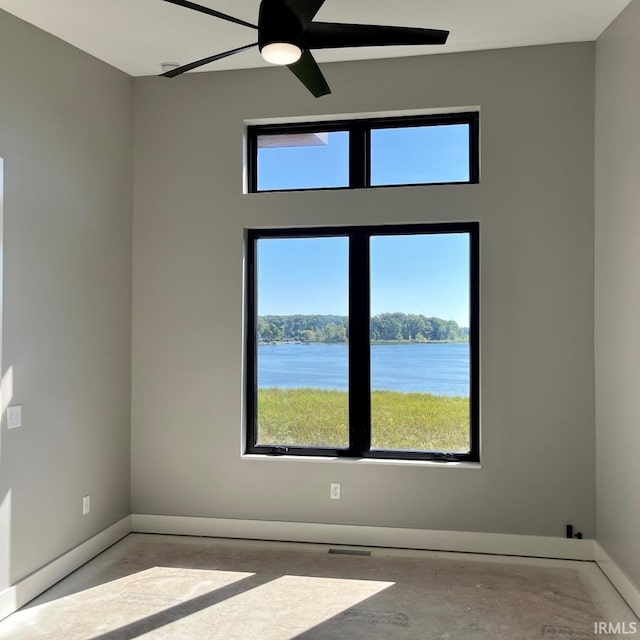 unfurnished room with a water view and ceiling fan