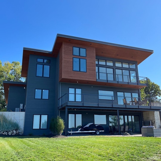 rear view of property with a balcony and a yard