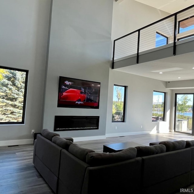 living room with a towering ceiling and wood-type flooring