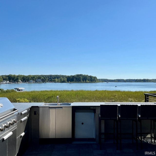 view of patio / terrace with area for grilling, a water view, and sink