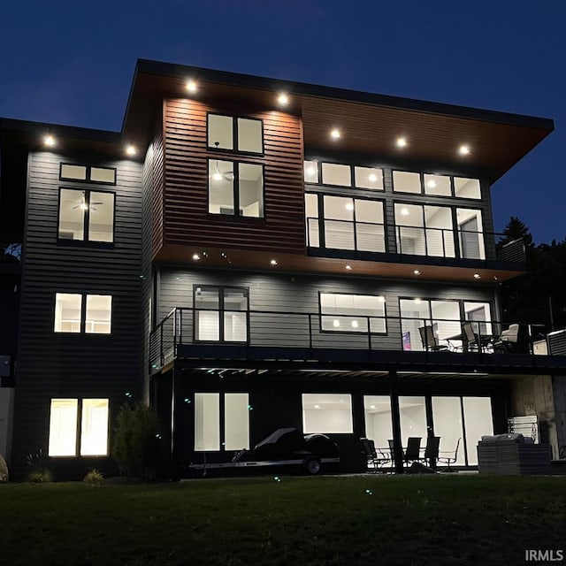 back house at twilight featuring a balcony