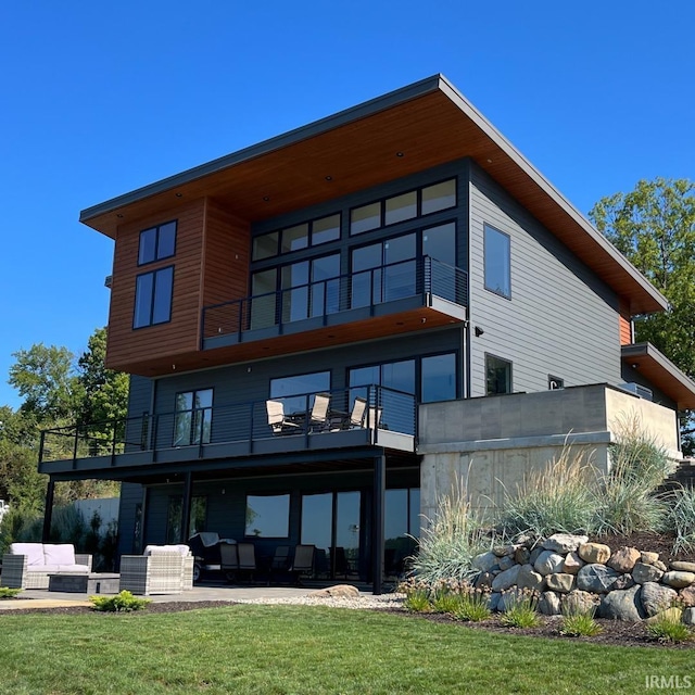 back of property featuring a patio area, outdoor lounge area, a balcony, and a lawn