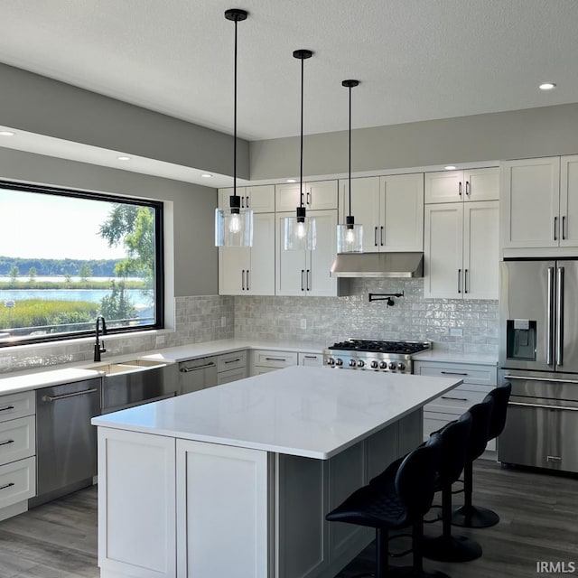 kitchen with a breakfast bar, white cabinetry, appliances with stainless steel finishes, a kitchen island, and pendant lighting