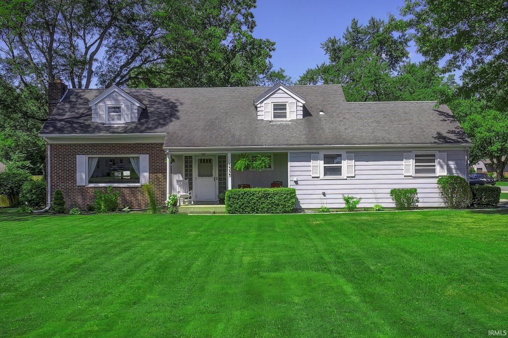 new england style home featuring a front yard and a porch