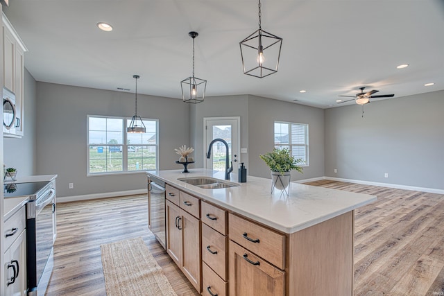 kitchen featuring sink, light hardwood / wood-style floors, an island with sink, decorative light fixtures, and light brown cabinets