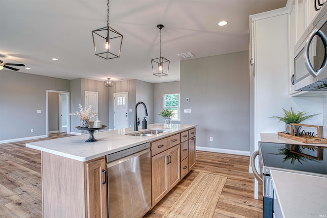 kitchen featuring light brown cabinetry, sink, appliances with stainless steel finishes, an island with sink, and pendant lighting