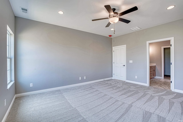 unfurnished bedroom featuring connected bathroom, light colored carpet, and ceiling fan