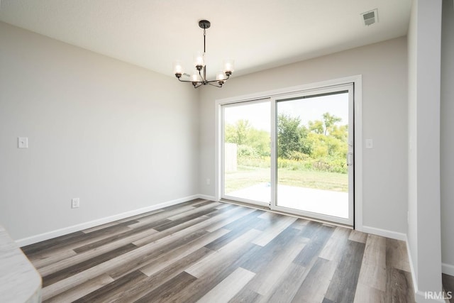 empty room featuring dark hardwood / wood-style floors and an inviting chandelier