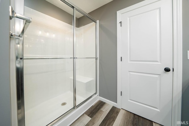 bathroom with hardwood / wood-style flooring and a shower with shower door