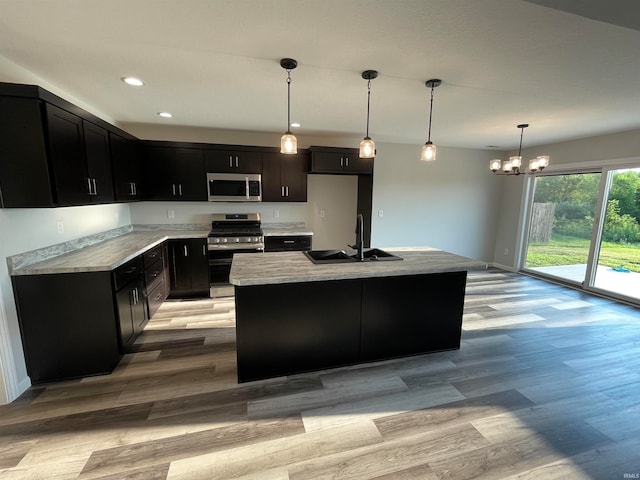 kitchen featuring light wood-type flooring, decorative light fixtures, stainless steel appliances, and sink