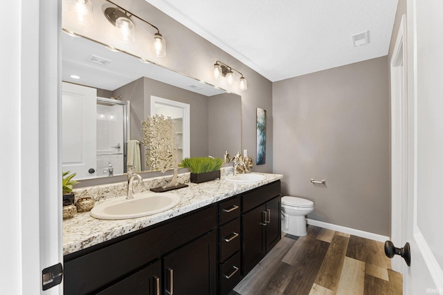 bathroom with toilet, vanity, an enclosed shower, and wood-type flooring