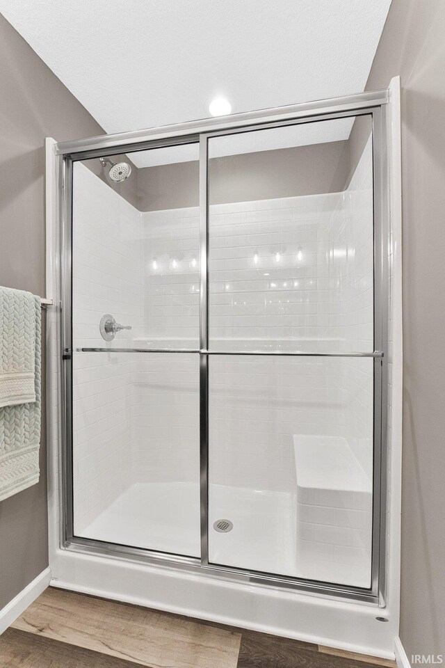 bathroom with an enclosed shower and wood-type flooring