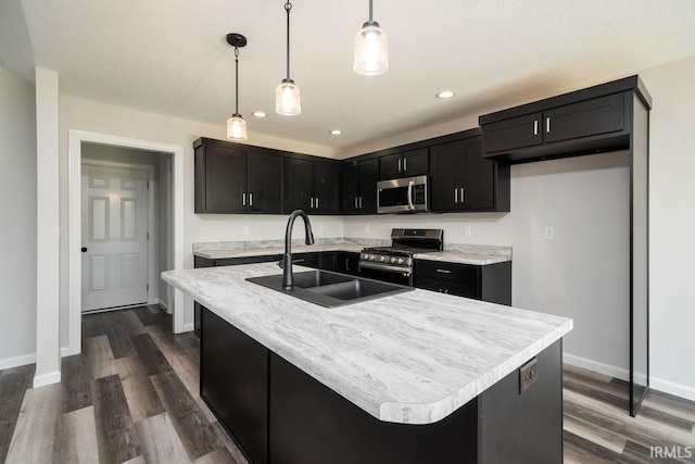 kitchen featuring appliances with stainless steel finishes, sink, hanging light fixtures, and an island with sink