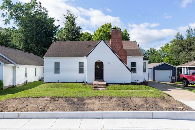 view of front facade featuring a garage, a front yard, and an outbuilding